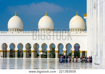 ABU DHABI, UNITED ARAB EMIRATES - DEC 28, 2017: Moslims and tourists are visiting the Sheikh Zayed Mosque in Abu Dhabi. It is the largest mosque in the country.