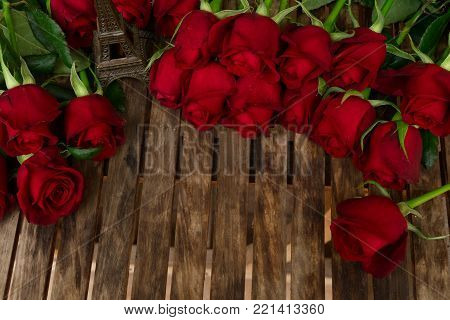 red fresh roses witheiffel tower on wooden table