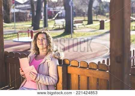 Young beautiful woman reading a love letter on Valentines / Womens Day at the park.