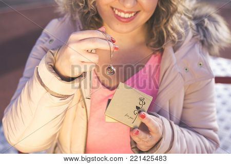 Young beautiful woman get a heart shape gold necklace gift from her boyfriend on Valentines Day.