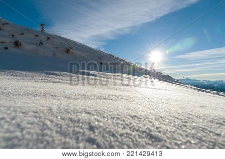 The landscape of snow-covered Caucasian rocks on the Gumbashi Pass. untouched snow under the pre-sun and the mountain ridge in the background. Russia, Northern Caucasus