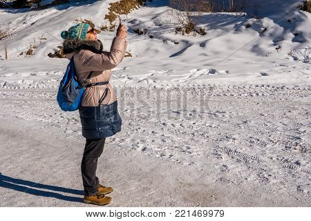 Woman 50 Years Old Taking Photo In The Mountains In Winter, Almaty, Kazakhstan