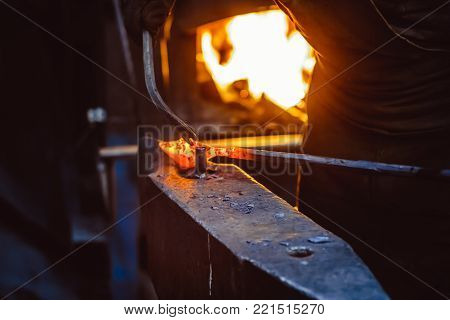 Blacksmith working on metal on anvil at forge high speed detail shot