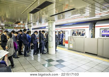 Tokyo, Japan - April 17, 2017: crowd of commuters waiting the Marunouchi Line, a subway line in red color and letter M, at Shinjuku Station, one of the most crowded railway lines in Tokyo.