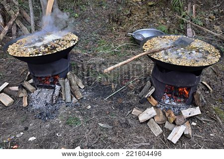 Cooking in the outdoor kitchen. Two metal barrels use as a wood-burning stove with wok pans with tofu goulash.