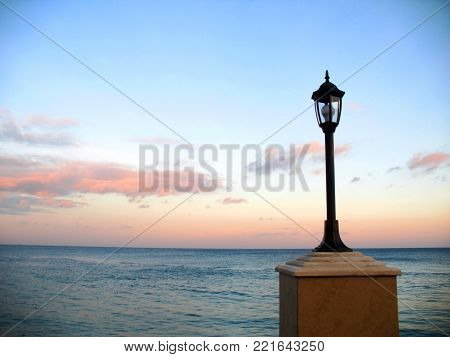 lantern on the embankment against the beautiful evening sky and the sea