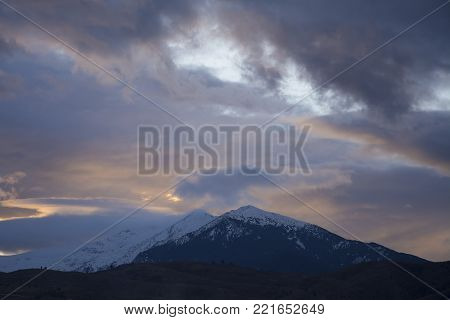 Cloudy sunset behind a snowy Macedonian mountain.
