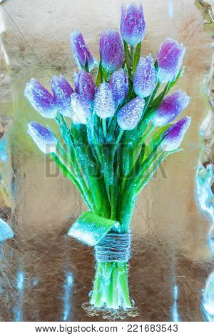 Close up bunch of violet tulips frozen in piece of ice