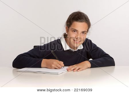 Colegial, escrevendo em sua mesa com uma expressão feliz