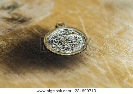 The work of jewelers. Trial jewelry of semiprecious metals. Round brooch with a braided pattern. Selective focus. Macro photo.