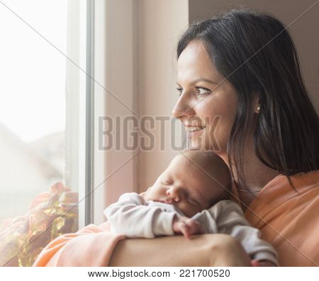a young mother enjoys the first days of motherhood with her child holding it in her arms