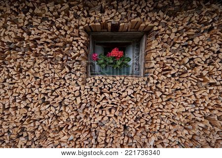 A stack of firewood piled up against the front wall of a farmhouse in the Italian Dolomites