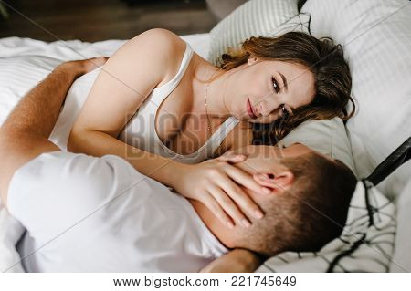 Woman hugging man in the bed, in a big bedroom. The Valentine's Day Concept. side view. Love story. Close up. Emotions of happiness.