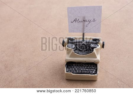 Retro syled tiny typewriter model on a brown background