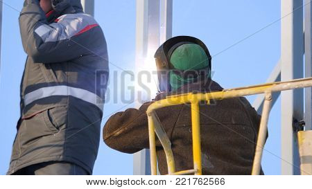 Construction Workers Working On Scaffolding, Man Working On The Working At Height With Blue Sky At C