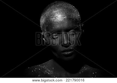 Portrait of a beautiful woman with creative body art glowing make up. Face is colored with black paint.