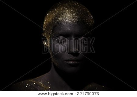 Portrait of a beautiful woman with creative body art glowing make up. Face is colored with black paint.