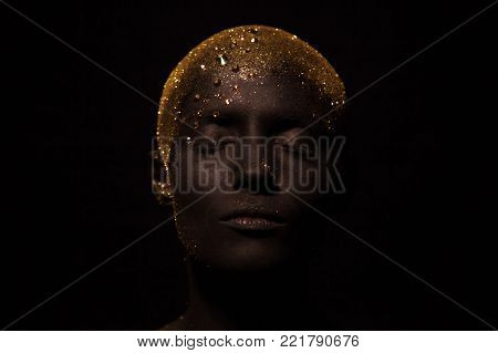 Portrait of a beautiful woman with creative body art glowing make up. Face is colored with black paint.