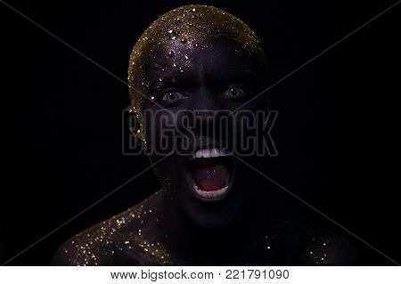 Portrait of a beautiful woman with creative body art glowing make up. Face is colored with black paint.