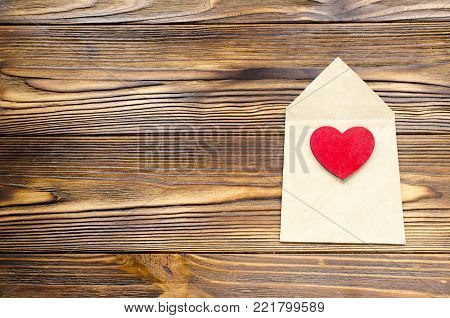 kraft paper envelope with wooden red heart on wooden table with copy space