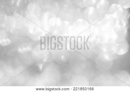 Silver glitter blur abstract background of bright sparkling white light glittering bokeh illumination for winter Christmas holiday decoration backdrop