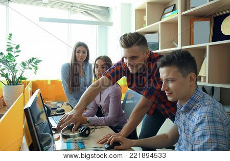 Group of young modern people in smart casual wear having a brainstorm meeting while standing in the creative office