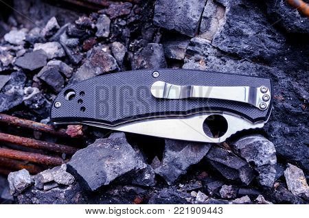 The reverse side of the knife. Black knife with an iron clip. Black object on a black background.