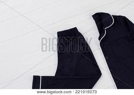 Boys dark blue pajama set. Folded shirt and pants on white table. Simple and elegant sleeping garments.