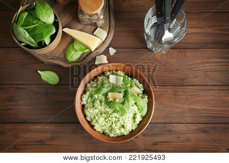 Dish with delicious spinach risotto on wooden table