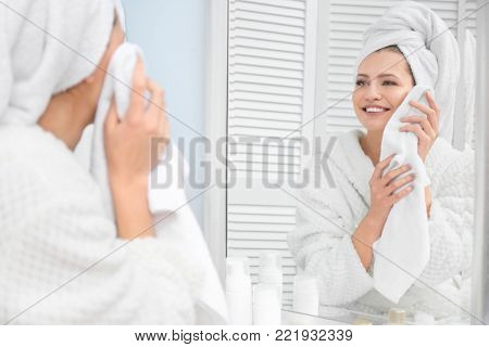 Young woman wiping her face with towel in bathroom