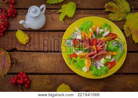 Autumn salad of jamon, lettuce, tomatoes, cheese. Wooden rustic background. Top view Selective focus