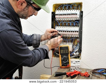 Technical electrician measures the voltage of a circuit breaker of a residential electrical panel