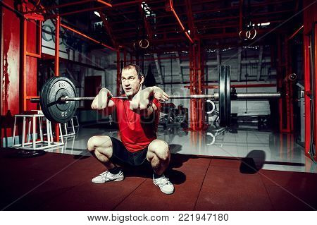 Muscular fitness man doing deadlift a barbell over his head in modern fitness center. Functional training. Snatch exercise