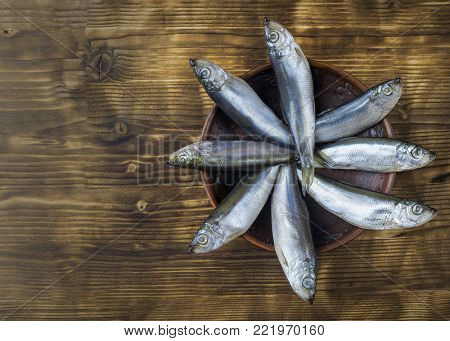 Salted herring in a clay bowl on wooden rustic table. The view from the top. Natural food from the ocean.