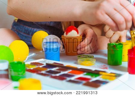 mother with kid painting eggs for easter