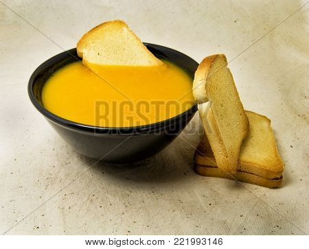 delicious pumpkin pured soup with potatoes and zwiebacks bread slices. for vegetarian, vegan and healthy concept