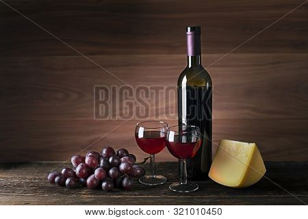 Glasses And Bottle Of Red Wine On Wooden Background