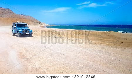 Egypt, Sharm El Sheikh - June 07, 2019: Blue Jeep Suv Rides On A Sandy Road Along The Seashore