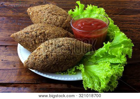 Fried Kibbeh With Tomato Sauce On A Plate, Over Rustic Wooden Table