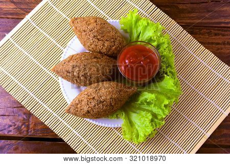 Fried Kibbeh With Tomato Sauce On A Plate, Over Rustic Wooden Table
