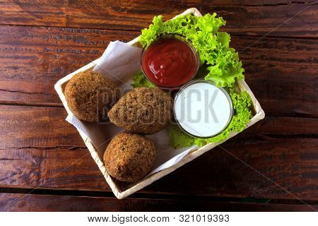 Fried Kibbeh With Tomato Sauce In A Basket, Over Rustic Wooden Table