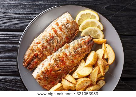 Grilled Mackerel Filet Served With Fried Potatoes And Lemon Slices Closeup On A Plate. Horizontal To