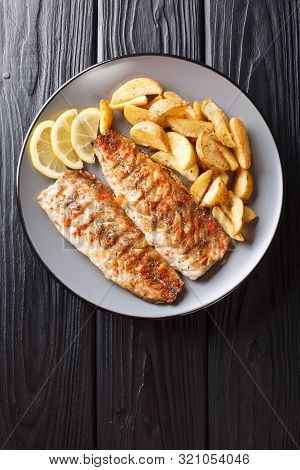 Serving Of Grilled Mackerel Fillet With Potato Wedges And Lemon Closeup On A Plate. Vertical Top Vie