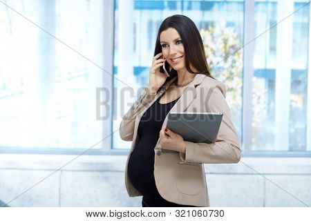Portrait of pregnant businesswoman - Happy pregnant woman on the phone in business dress working in office.