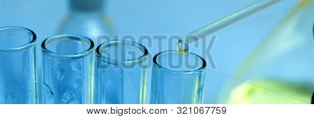 Pipette Tip With A Droplet Over A Rack Of Eppendorf Test Tubes. Close Up. Blue Toning.