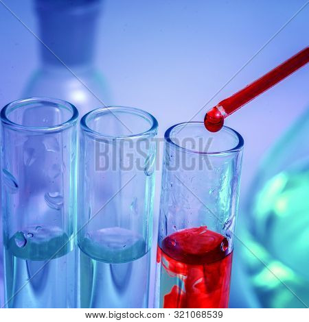 Pipette Tip With A Droplet Blood Over A Rack Of Eppendorf Test Tubes. Close Up. Blue Toning.