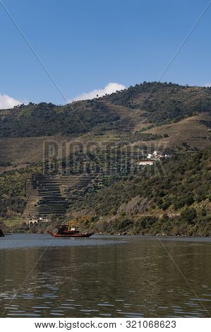 Scenic View Of The Douro River With A Traditional Rabelo Boat And Terraced Vineyards Near The Tua Vi