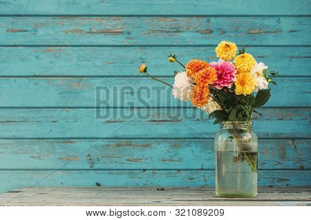 Fall Flowers In Glass Jars Standing On The Table Outside