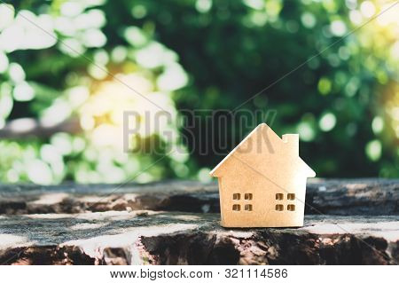 Closed Up Tiny Home Model On Floor Or Wood Board With Sunlight Green Bokeh Background. House Propert