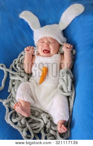 A Child In A Bunny Costume With A Carrot Screams. Isolated On Blue Background. The Concept Of Freedo